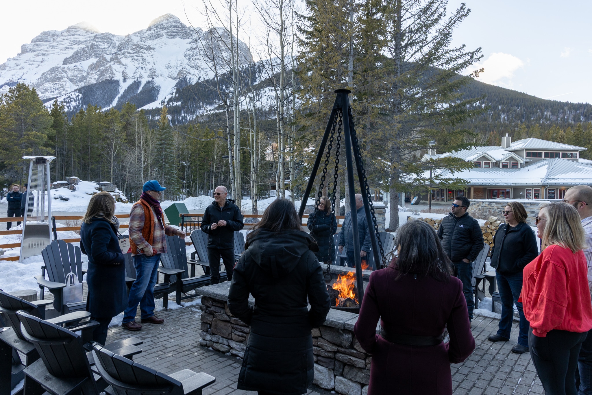 Group of BEx attendees gathered around outdoor stone fire pit with mountain behind