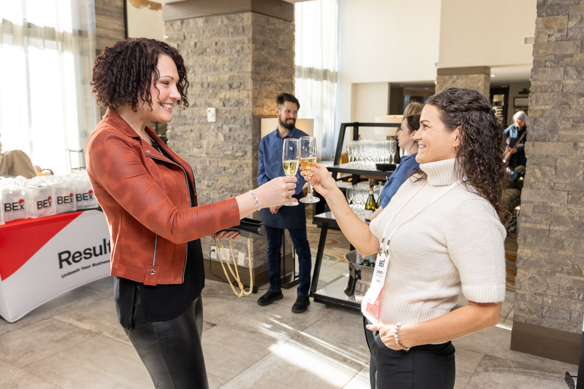 Two women toasting with champagne glasses in the BEx lodge lobby